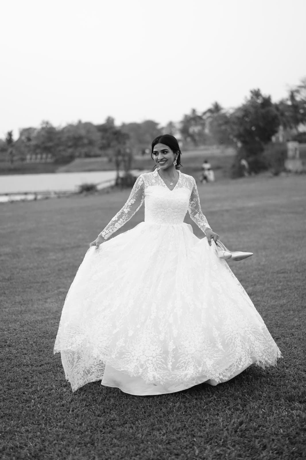 Grace walking barefoot on grass in her gown, shoes in hand