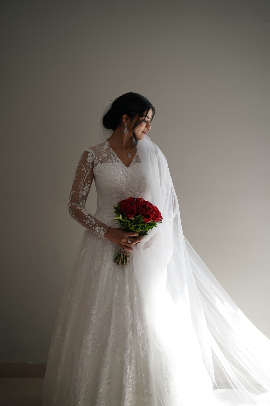 Grace in her own gown, holding red roses, looking to the side
