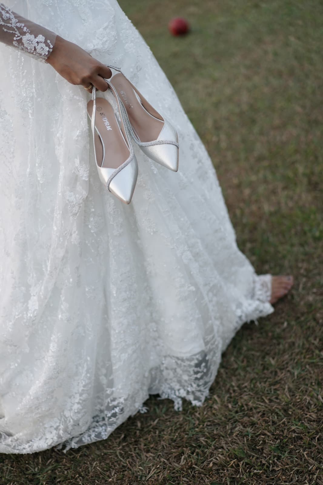 Bridal heels held against lace skirt detail