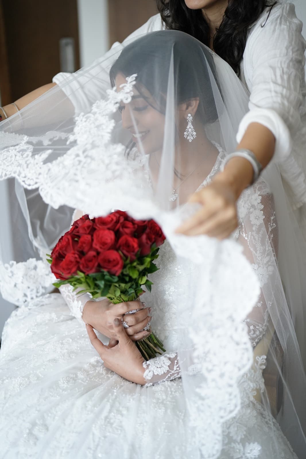 Veil being placed, bride holding red roses, intimate moment